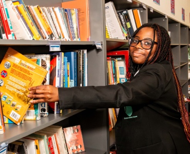 Student reaching for book from bookcase