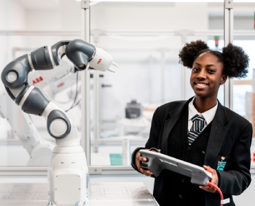 Smiling student controlling robotic arm